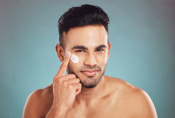 Portrait, beauty and lotion with a man in studio on a gray background to apply antiaging facial...