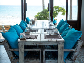 Dining set, spoons, forks, knives, glasses and placemats are arranged on a wooden table with wood...