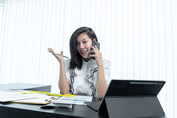 Happy business woman talking on mobile phone while analyzing weekly schedule in her notebook