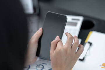 Young business woman on the phone at the office.Business woman texting on the phone and working on laptop.Beautiful young business woman sitting in office.Business woman smiling.