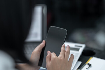 Young business woman on the phone at the office.Business woman texting on the phone and working on laptop.Beautiful young business woman sitting in office.Business woman smiling.