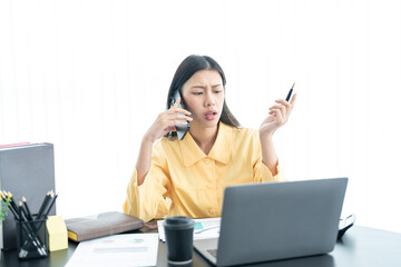 Young business woman on the phone at the office.Business woman texting on the phone and working on laptop.Beautiful young business woman sitting in office.Business