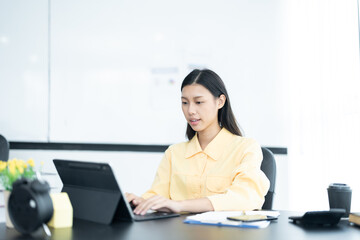 Portrait of pretty cheerful girl smiling while working on laptop in office