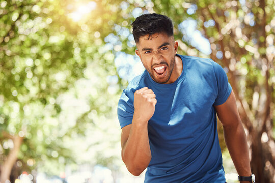 Running, portrait and a man celebrate outdoor for exercise, training or fitness goals. Excited Indian male athlete with a fist in nature for a workout, run and performance target, success or win