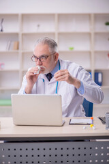 Old male doctor working in the clinic