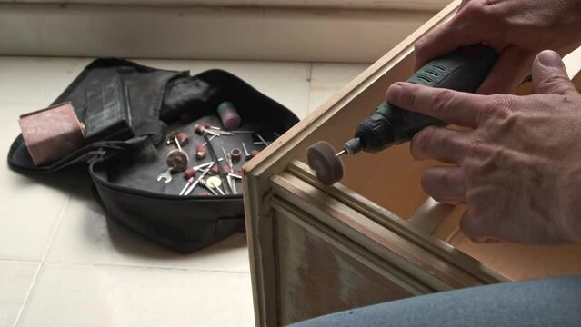 man's hands sanding with electric rotary sander a wooden furniture. person doing DIY
