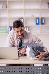 Young male employee unhappy with excessive work in the office