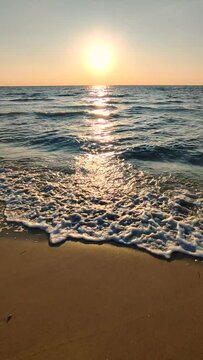Dawn on sea. Sunset on sea. Sunrise, sunset on ocean. Glowing sun, blue waves, sand beach. Sun sunshine light. Seascape waterscape landscape. Seaside seashore. Natural background, nature. Vertical