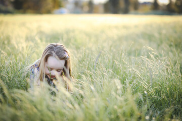 Lovely caucasian girl with long hair lying in long grass at the park with big smile