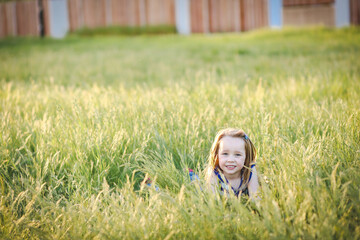 Lovely caucasian girl with long hair lying in long grass at the park with big smile