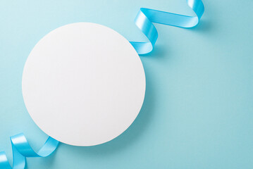 Top view photo of white empty circle with a pastel blue ribbon on an isolated light background with...