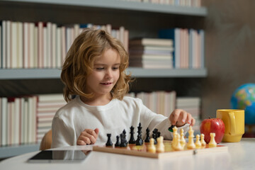 Kid playing chess in the room. Child playing chess. Clever kid thinking about chess.