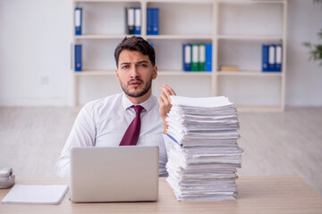 Naklejka premium Young male employee and too much work in the office