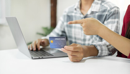 E-commerce Concept. Happy couple holding credit card enjoying doing online shopping and using laptop enter their card number in-app to purchase and payment in internet store