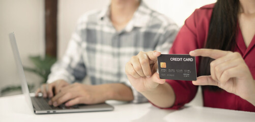 E-commerce Concept. Happy couple holding credit card enjoying doing online shopping and using laptop enter their card number in-app to purchase and payment in internet store