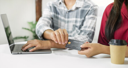 E-commerce Concept. Happy couple holding credit card enjoying doing online shopping and using laptop enter their card number in-app to purchase and payment in internet store