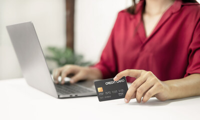 The businesswoman hand holding credit card enjoying doing online shopping and using laptop enter their card number in-app to purchase and payment in internet store