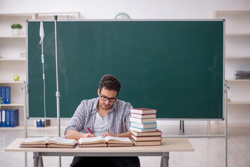 Young male teacher suffering in the classroom