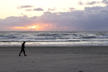 Sunset on the sandy shore of the North Sea in the Netherlands with windmills in background in bokeh