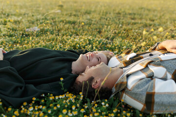 Side view of relaxed young couple lying together on green grass with eyes closed. Relationships and...