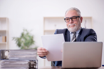 Fototapeta premium Old male employee and too much work at workplace