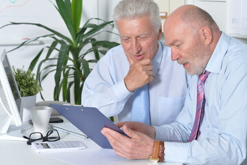 Two old business men sitting at desk and working