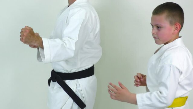 On a white background, athletes with yellow and black belts kick kicks