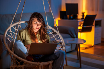 Woman working remotely from home late at night using laptop computer