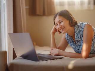 Happy young asian woman with laptop resting in bedroom in tiny house, weekend away and remote office idea. Tiny houses and Small Living concept.