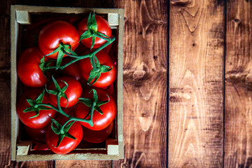 Tomatoes in a wooden box on a wooden background. Selective focus.