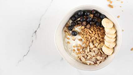 Homemade granola with Greek yogurt, almonds, blueberries and banana in a bowl. Copy space