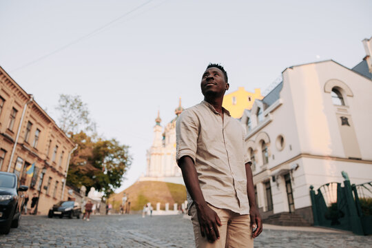 Young african man is standing among street during walk in city.
