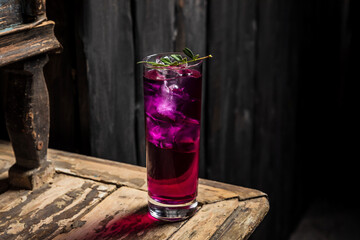Gin and tonic cocktail made with purple gin served on ice in a highball cocktail glass garnished with green sprig - 608138037