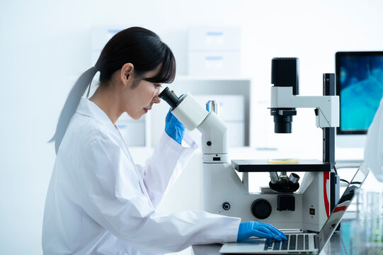 A female scientist conducting research under a microscope