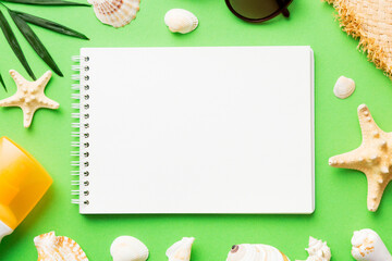 Blank writing book with summer beach accessories on background, copy space. Flat lay with copy space