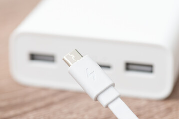 Close up of power bank with micro usb cable on the foreground. Using external smart battery for charging devices