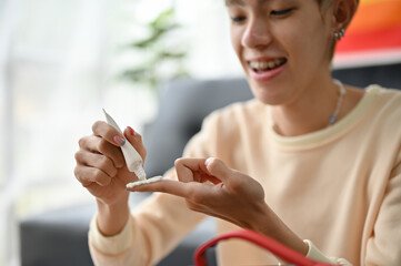 A happy young Asian gay man is squeezing sunscreen on his finger, applying sunscreen