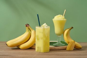 Concept for advertising product with banana ingredient. Ripe bananas and glasses of juice and banana smoothie on a wooden table. Bananas are one of the most consumed fruits in the world