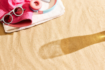 Shadow of beer glass on warm sand with beach stuffs. Beach chill on warm summer day with cool drink. Concept of alcohol drink, taste, summer vacation, holiday, brewery. Advertisement