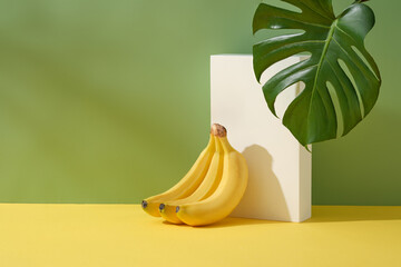 Minimal scene with a banana bunch leaning on rectangle podium in white color. Banana (Musaceae)...