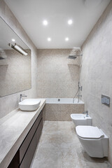white marble bathroom with toilet, bidet and sinks