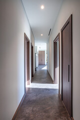 empty corridor with white walls and wooden doors to other rooms