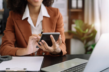 Businesswoman working with tablet and using a calculator to calculate the numbers of static in...