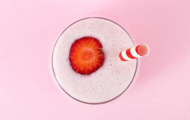 Strawberry milkshake in glass on pink background, top view