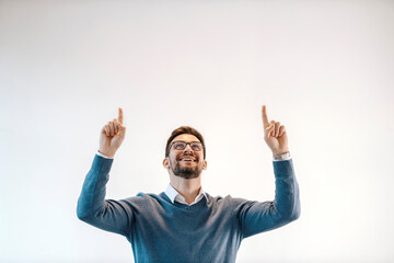 Happy businessman is pointing up at blank pace and looking up.