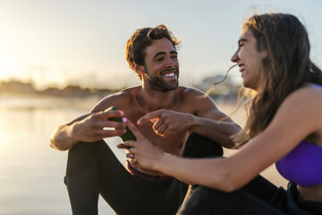 Surfers shitting on shore, laughing and pointing at the phone.