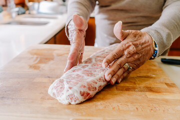 The hands of a old retired grandmother prepares a raw piece of meat, meatballs.