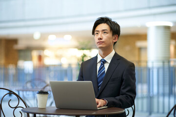 Fototapeta premium ノートパソコンを使用してリモートワークを行うスーツ姿の日本人ビジネスマン