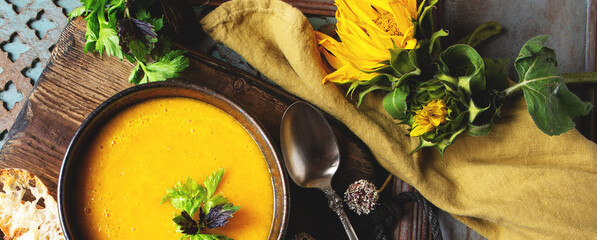 bowl with traditional spanish yellow tomato gazpacho soup on wooden table