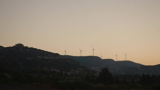 Wide shot night sunset dusk in mountains on Cyprus. Twilight nature with windmills spinning in slow motion outdoors